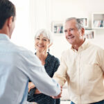 An elderly couple greeting a man